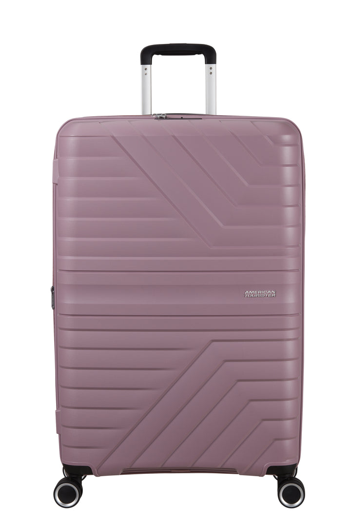 A hardshell spinner suitcase in a dusty mauve-pink color with a geometric chevron pattern, featuring an extended telescopic handle and four multi-directional wheels.