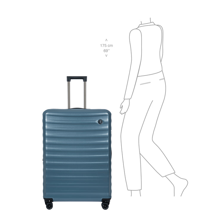 Blue Bric's suitcase with dimensions shown next to a person for scale on a white background