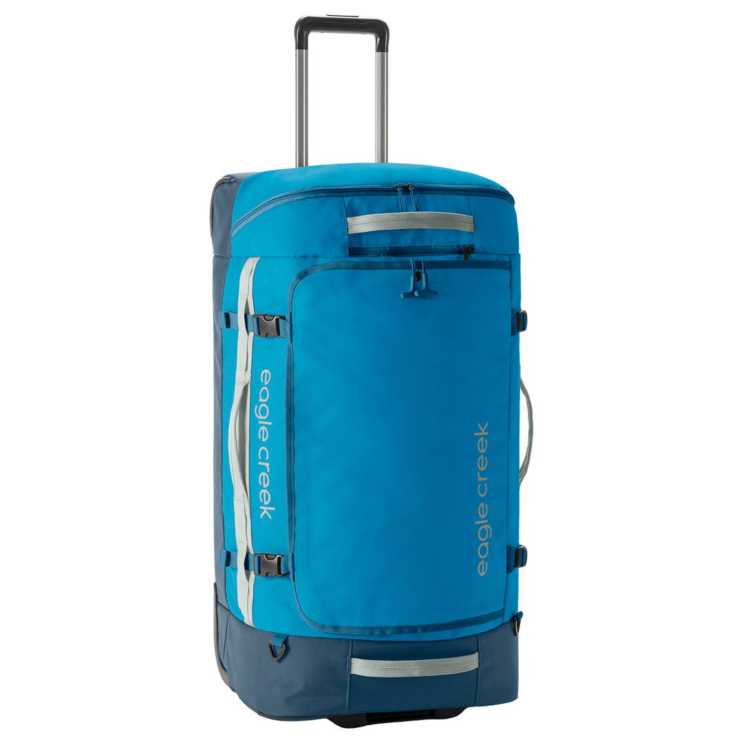 A bright blue and navy Eagle Creek rolling duffel bag with an extended telescoping handle, shown on a plain white background.