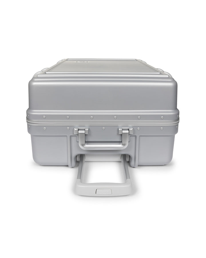 A silver aluminum hard case with a hinged lid, front handle, and extended lower handle, shown on a plain white background.