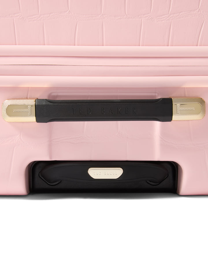 Close-up of a pink suitcase with black and gold handle