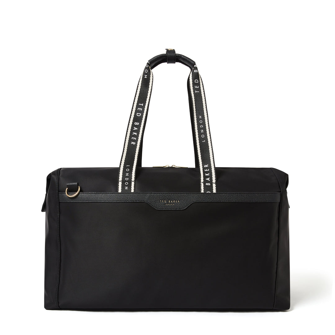 A black Ted Baker duffel bag with white and black patterned shoulder straps and a small gold-tone logo plate on the front.