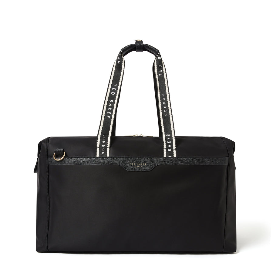 A black Ted Baker duffel bag with white and black patterned shoulder straps and a small gold-tone logo plate on the front.