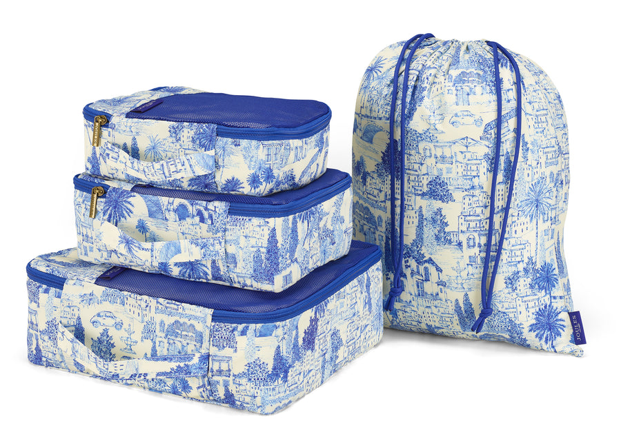 Set of blue and white toile-patterned packing cubes with a matching drawstring bag on a white background