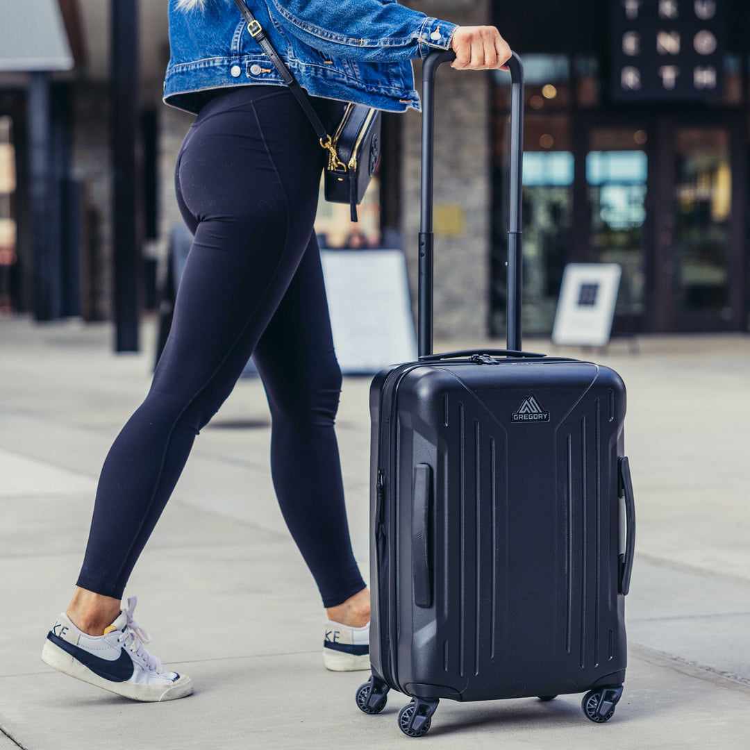 Person walking with a black suitcase in an urban setting
