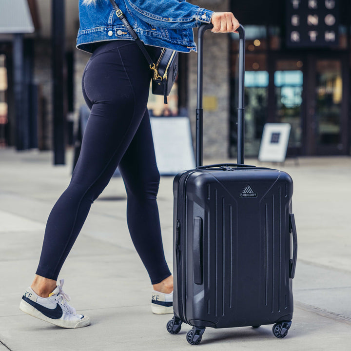 Person walking with a black suitcase in an urban setting