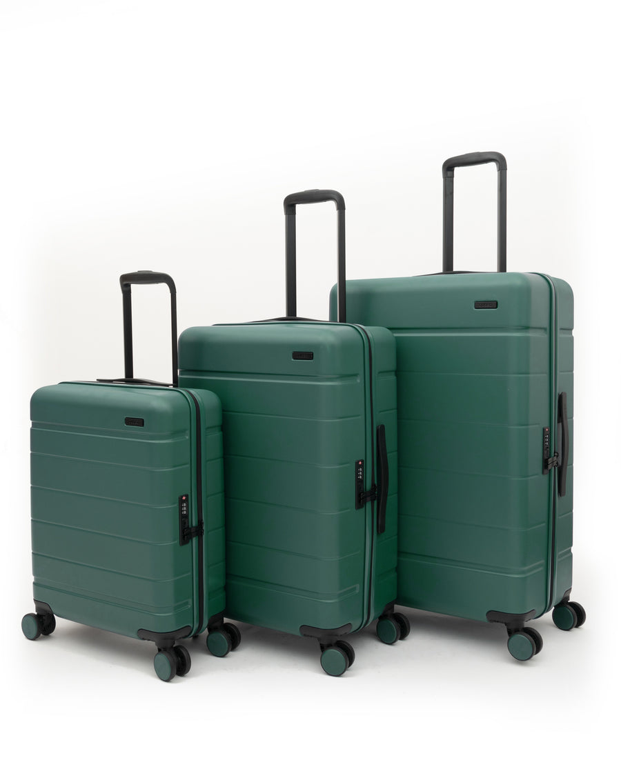 Three hard-shell spinner suitcases in a matching dark green set, arranged by size from left to right, with telescoping handles extended, on a clean white studio background.