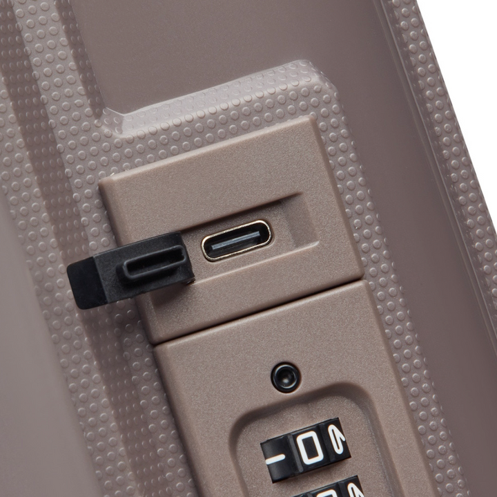 Close-up of a suitcase with USB-C port and combination lock on a textured surface.