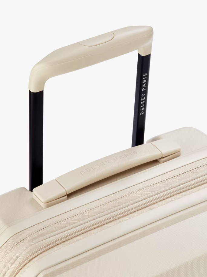 Close-up of a beige suitcase with handle and visible Delsey Paris brand name on a white background
