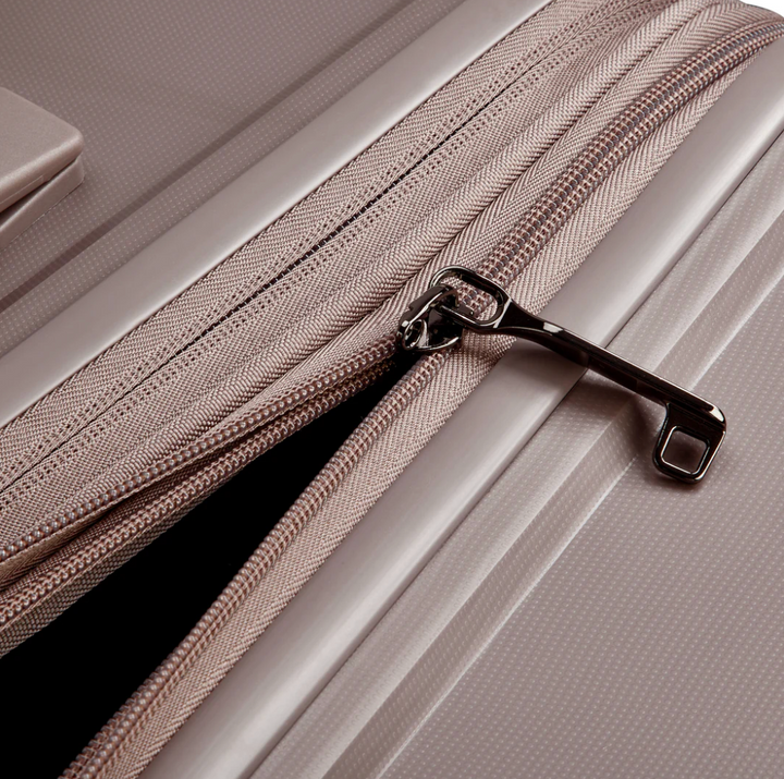 Close-up of a brown Delsey suitcase zip puller with a zipper