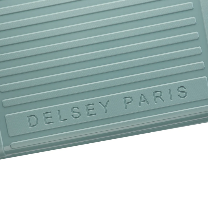 Close up of a sage green suitcase with 'Delsey Paris' branding on a white background