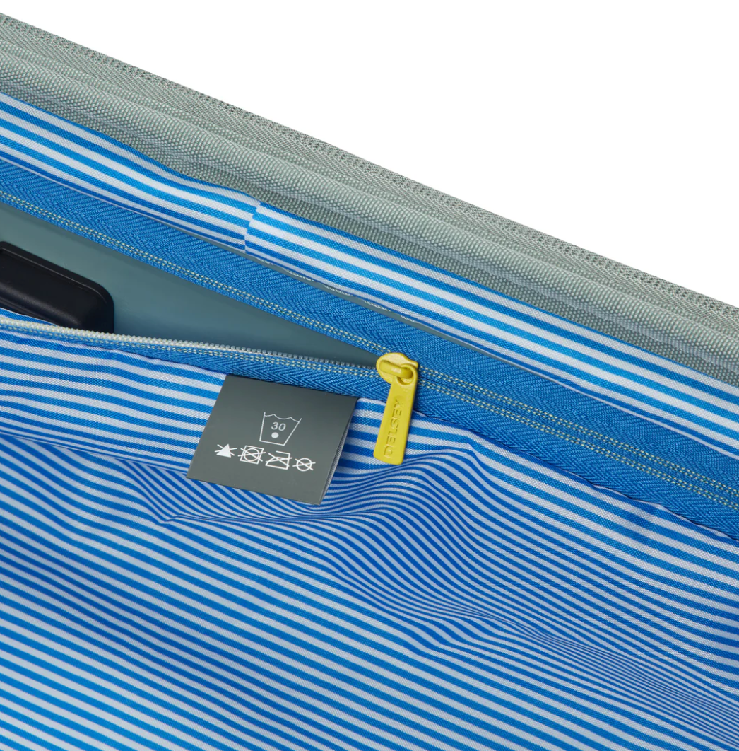Close-up of a sage green suitcase lining with blue stripes and yellow zipper
