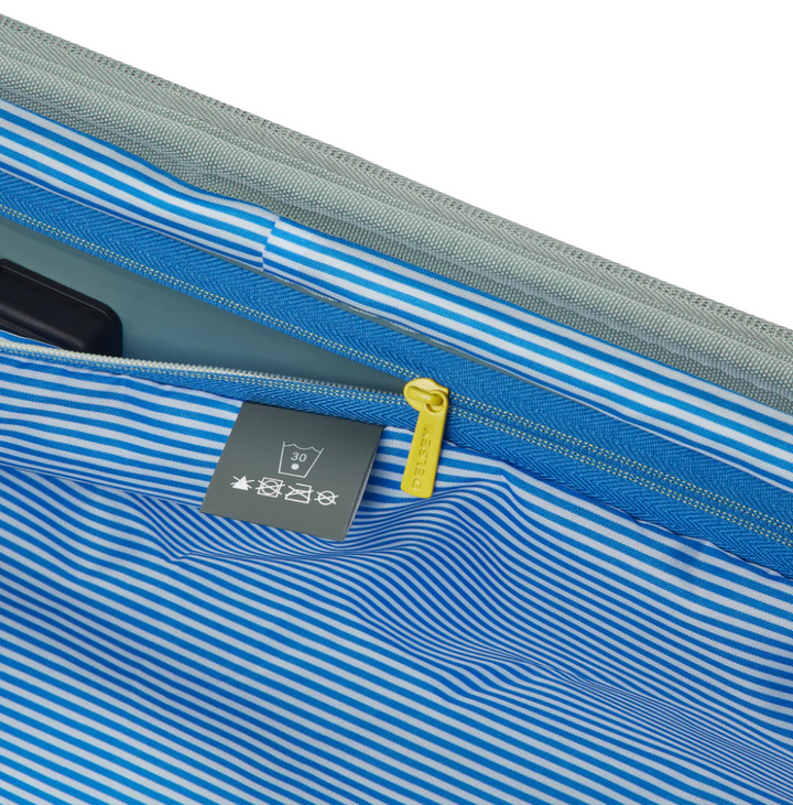 Close-up of a sage green suitcase lining with blue stripes and yellow zipper