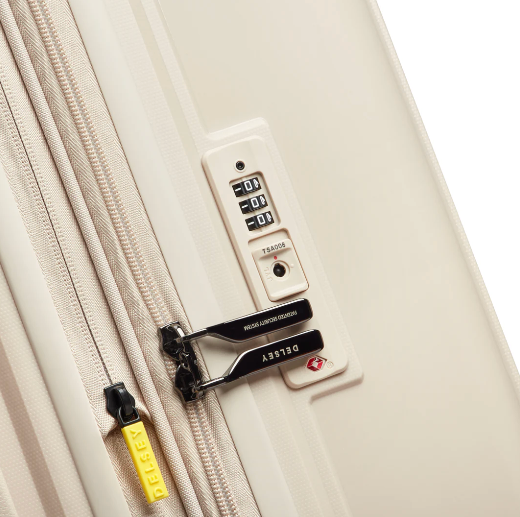 Close-up of a beige suitcase with a combination lock and DELSEY branding on the zip pullers.