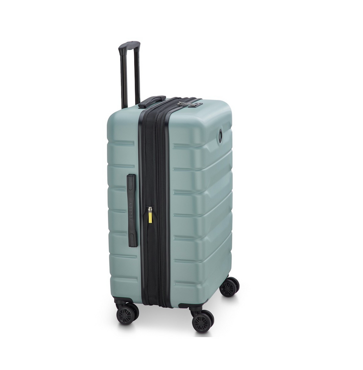 Side angle of a Sage Green Delsey suitcase with black wheels and handle on a white background