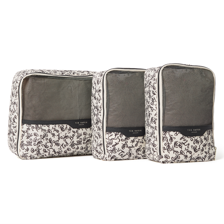 Set of three Ted Baker ribbon-patterned packing cubes with mesh and PU finishes and Ted Baker branding on a white background