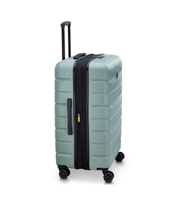 Side angle of a Sage Green Delsey suitcase with black wheels and handle on a white background