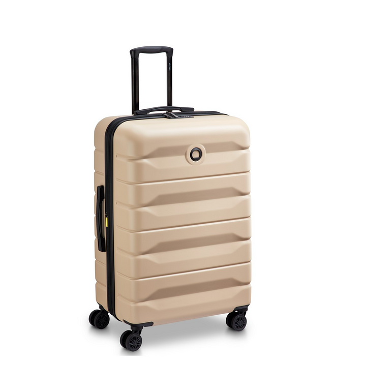 Beige Delsey suitcase with black handle and wheels on a white background