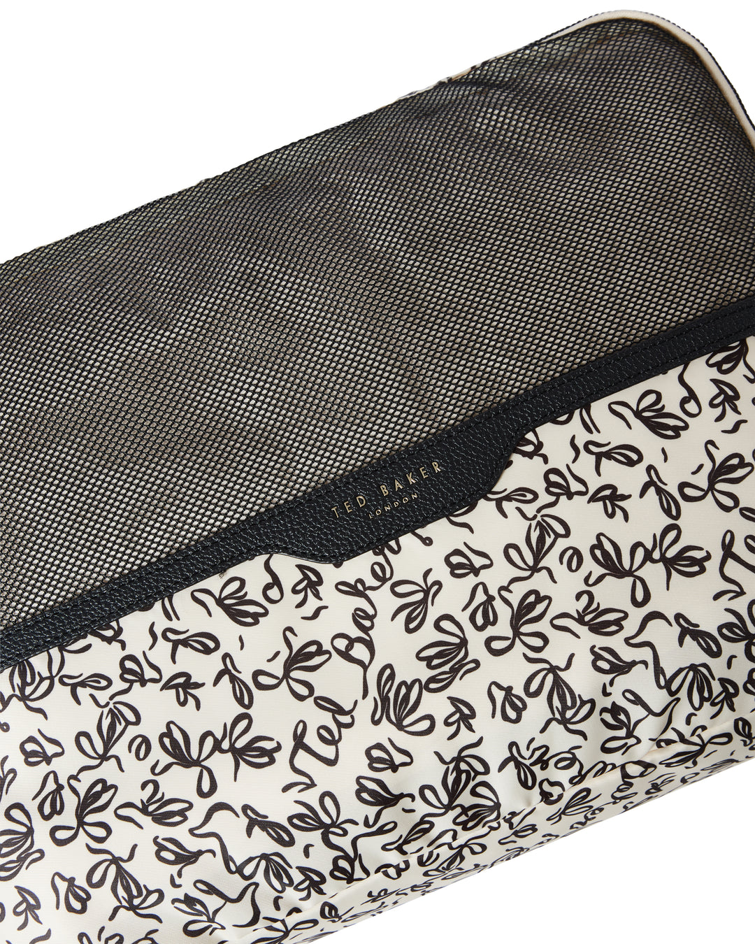 Close up of a Ted Baker packing cube with Ted Baker branding and breathable mesh. Lining print is black ribbon design on cream on a white background