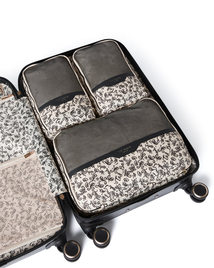 Set of 3 Ted Baker ribbon-patterned packing cubes inside a suitcase on a white background