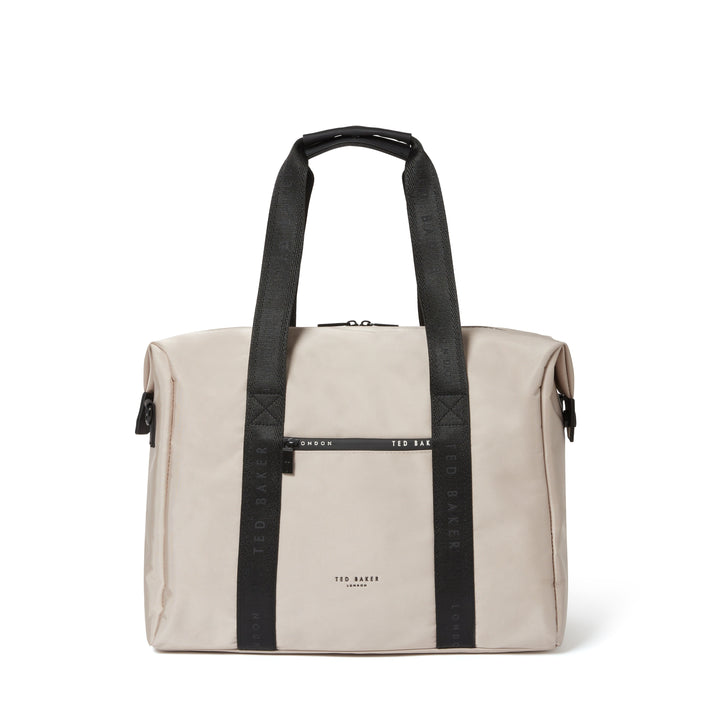 A beige canvas duffel bag with black webbed handles and a black horizontal strap detail across the front, featuring the brand name 'TED BAKER' printed in black on the front.