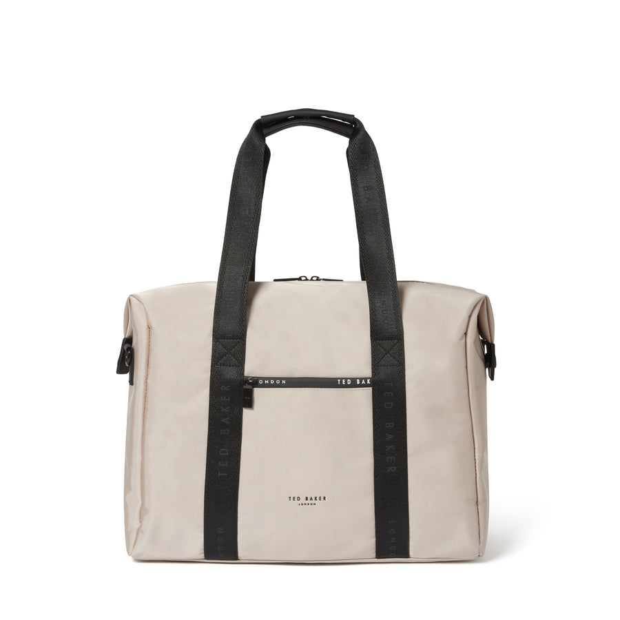 A beige canvas duffel bag with black webbed handles and a black horizontal strap detail across the front, featuring the brand name 'TED BAKER' printed in black on the front.