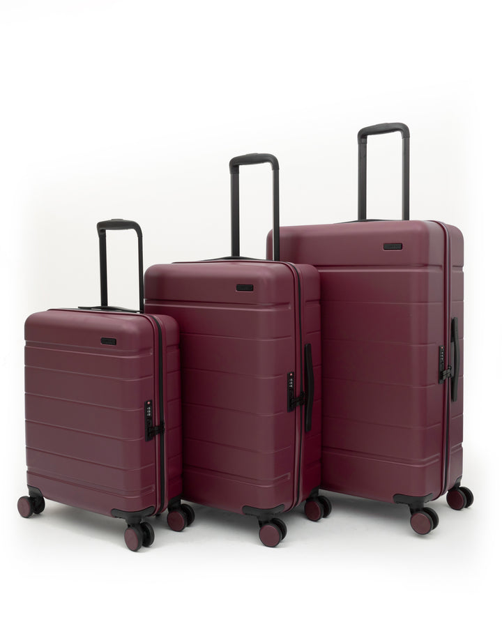 Three-piece hardside spinner luggage set in burgundy, shown in different sizes against a clean white background.