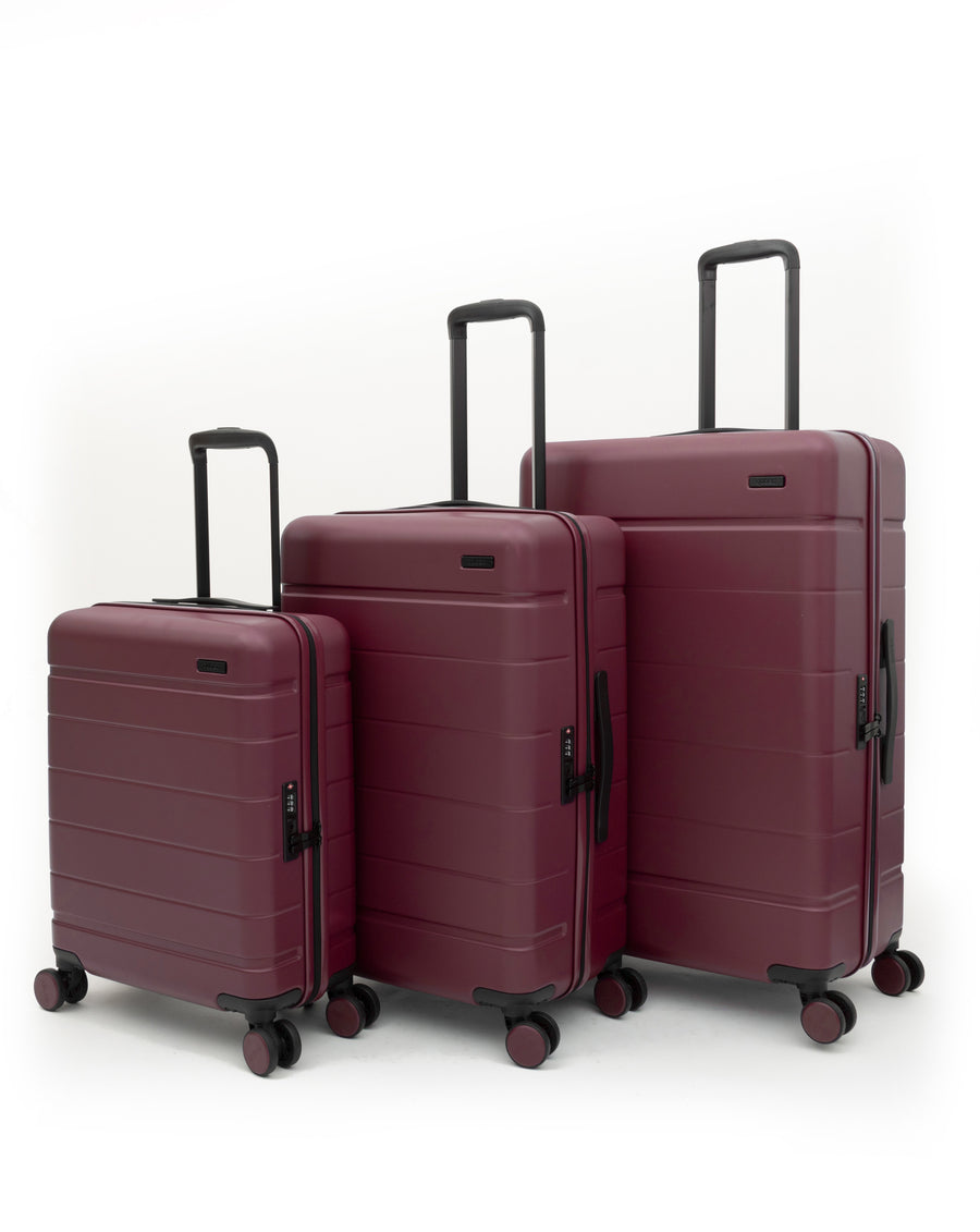 Three-piece hardside spinner luggage set in burgundy, shown in different sizes against a clean white background.