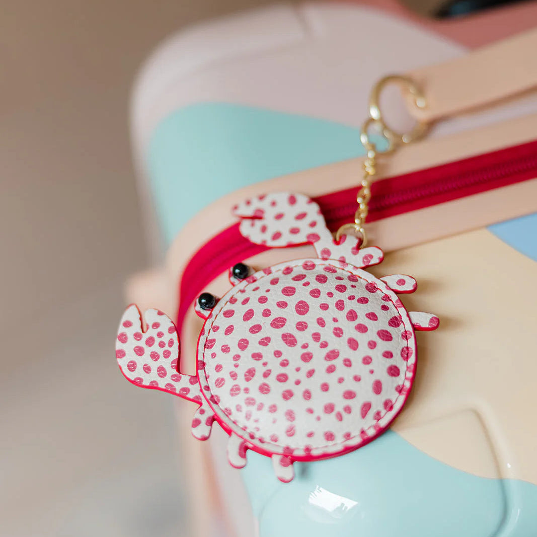Close-up of a colorful bag with a red and white polka dot luggage tag attached.