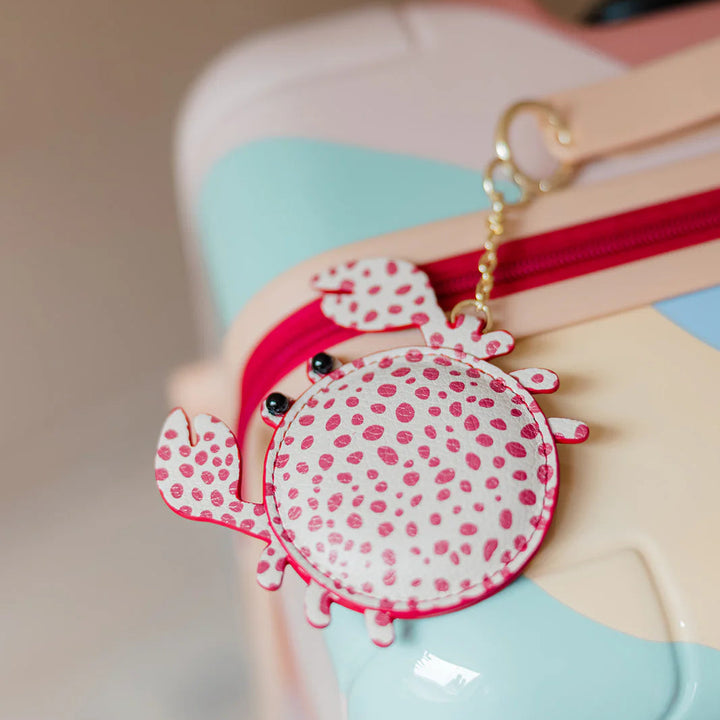 Close-up of a colorful bag with a red and white polka dot luggage tag attached.