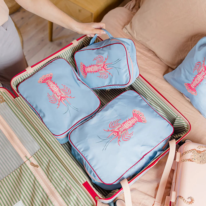 Set of blue travel packing cubes with red accents and lobster design 