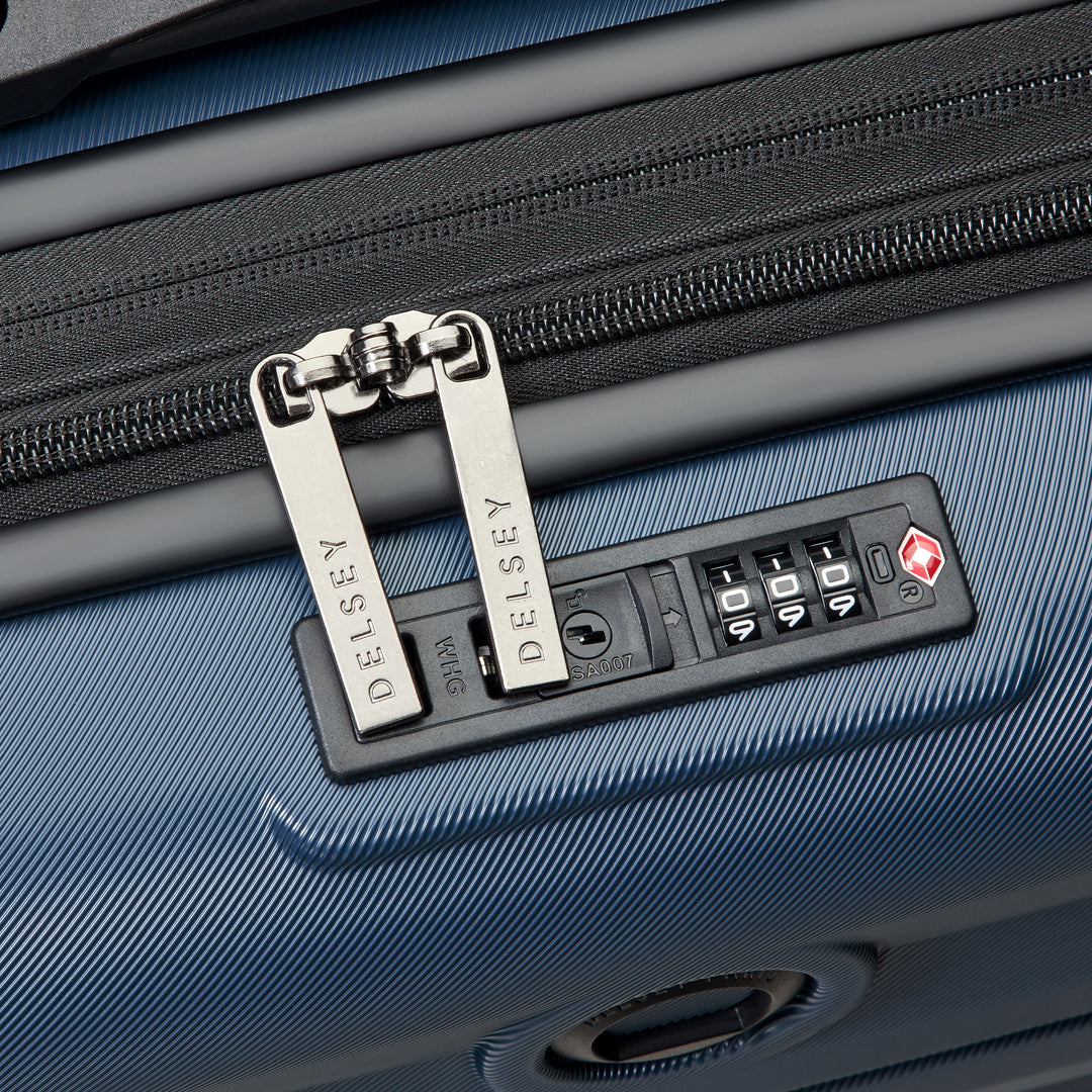 Close-up view of a blue suitcase with a combination lock and Delsey zip branding.