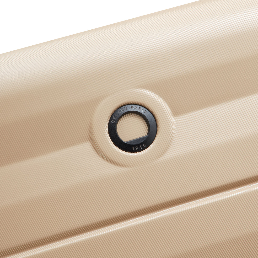 Close-up of a beige suitcase with Delsey branding on a white background