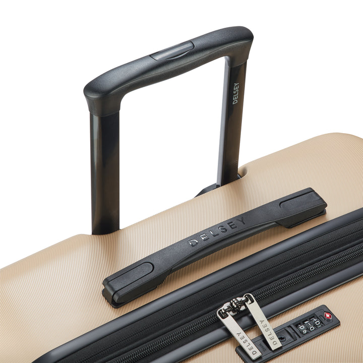 Close-up of a beige suitcase with a black handle and zipper, featuring the 'Delsey' branding.