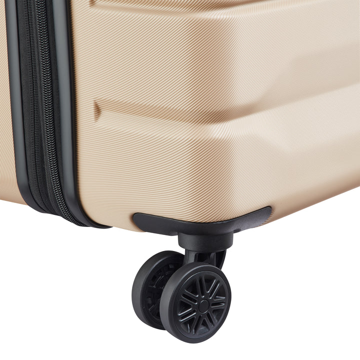 Close-up of a beige suitcase with a black wheel on a white background