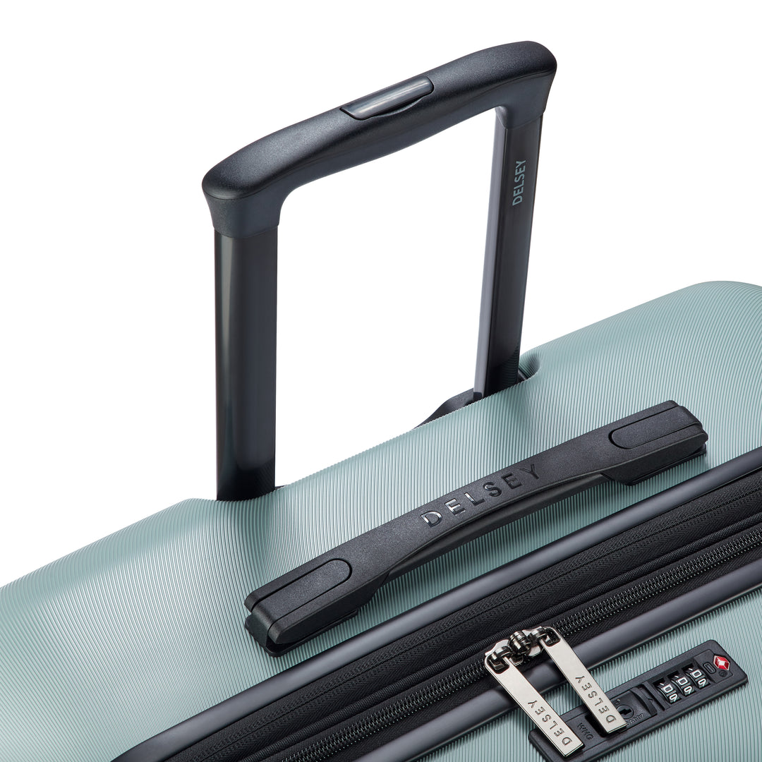 Close up of a sage green suitcase with black handle and Delsey branded zip pullers