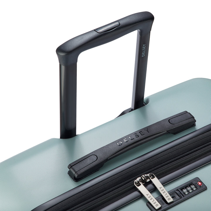 Close up of a sage green suitcase with black handle and Delsey branded zip pullers