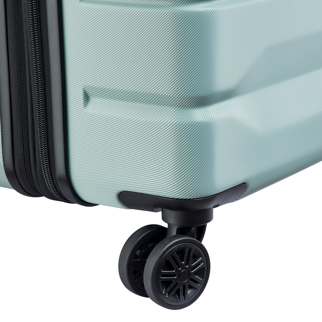 Close-up of a sage green suitcase with a black wheel on a white background