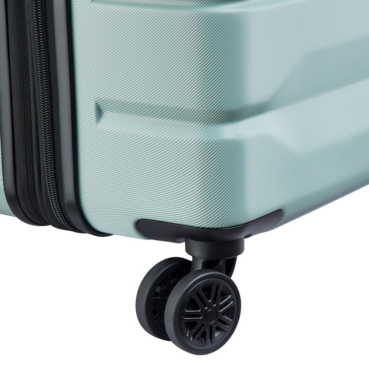 Close-up of a sage green suitcase with a black wheel on a white background